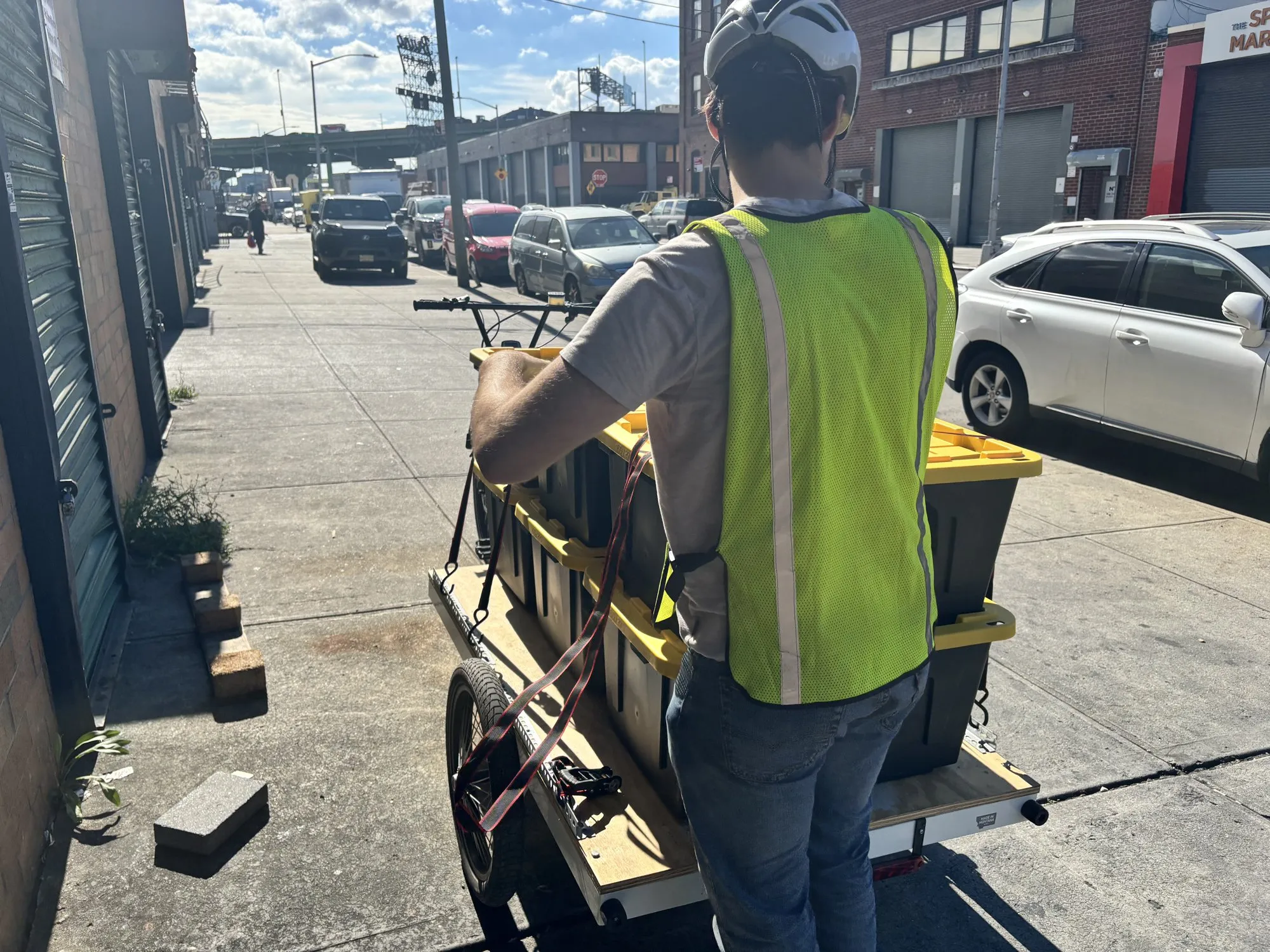 Courier loading totes onto a cargo bike trailer
